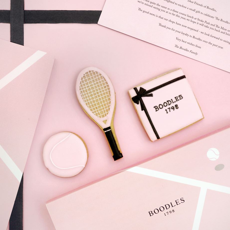 Boodles Tennis Week bespoke biscuits by Biscuiteers: pastel pink gift box, tennis racket, ball, and branded sleeve.