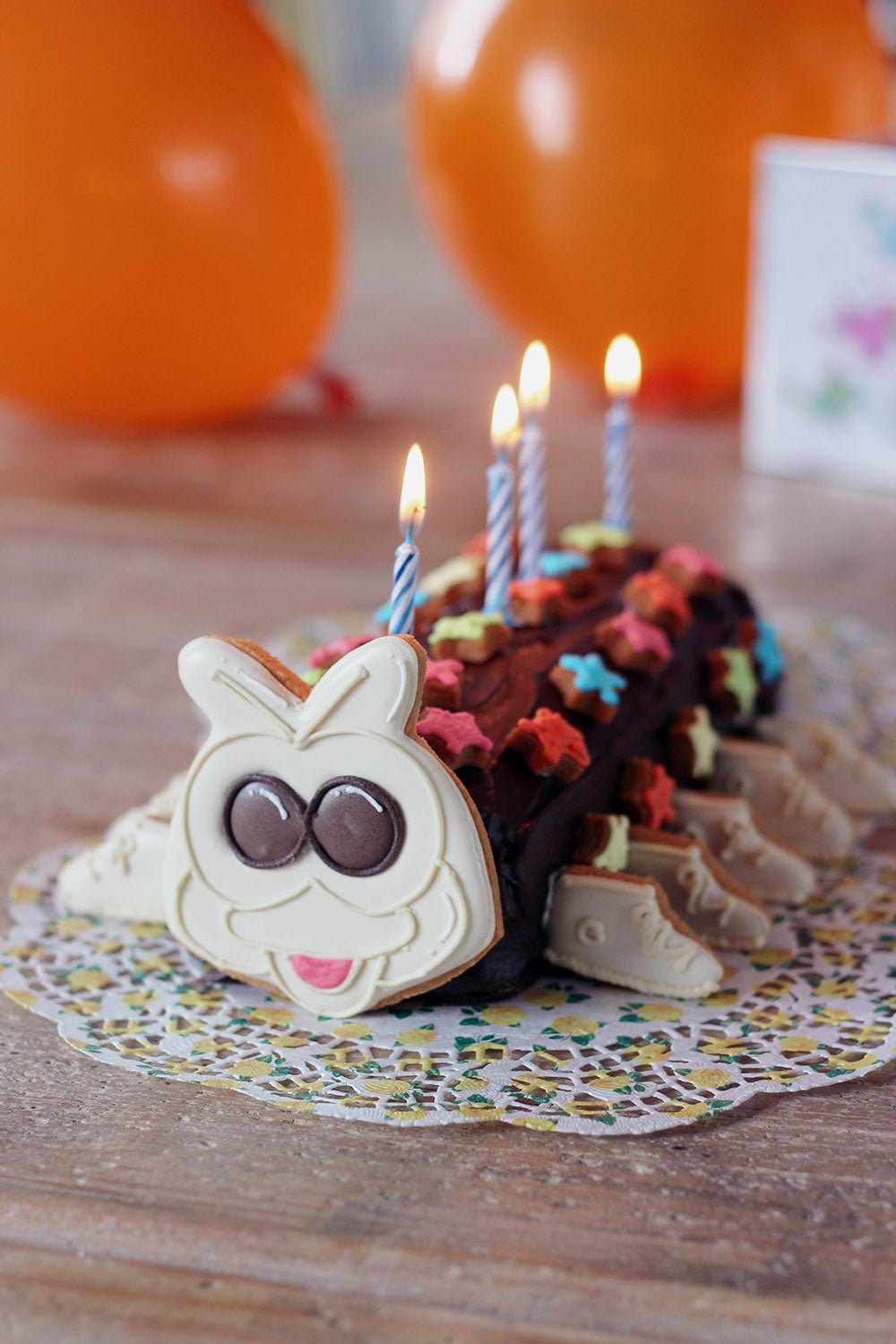 Chocolate caterpillar cake with colorful decorations, perfect for children's birthday parties by Biscuiteers.