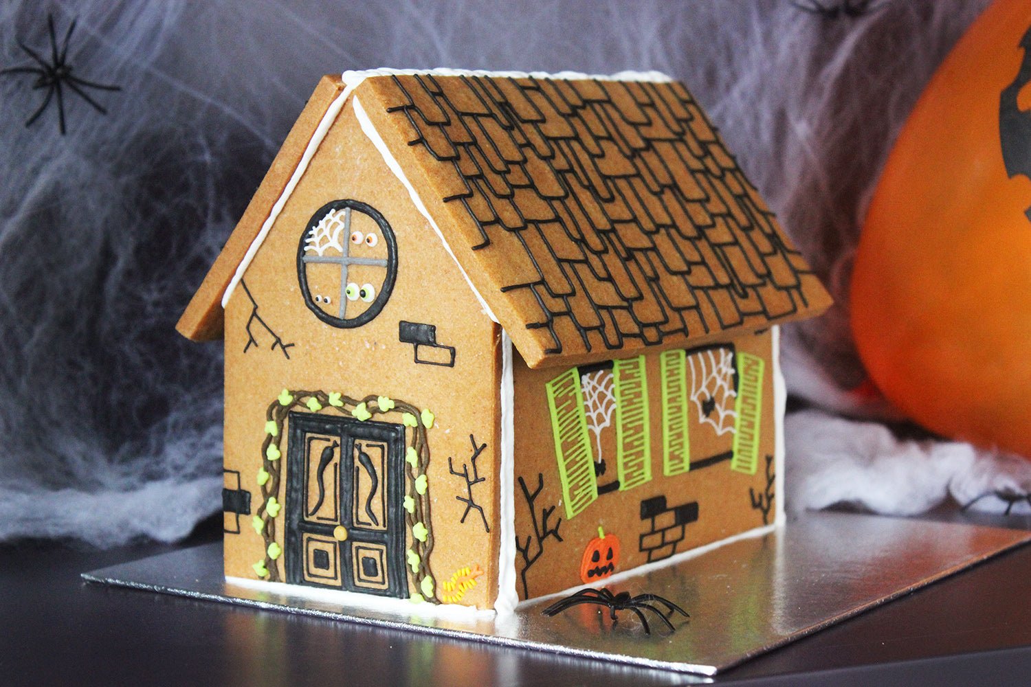 Halloween gingerbread house with spooky decorations, perfect for personalized gifts by Biscuiteers.
