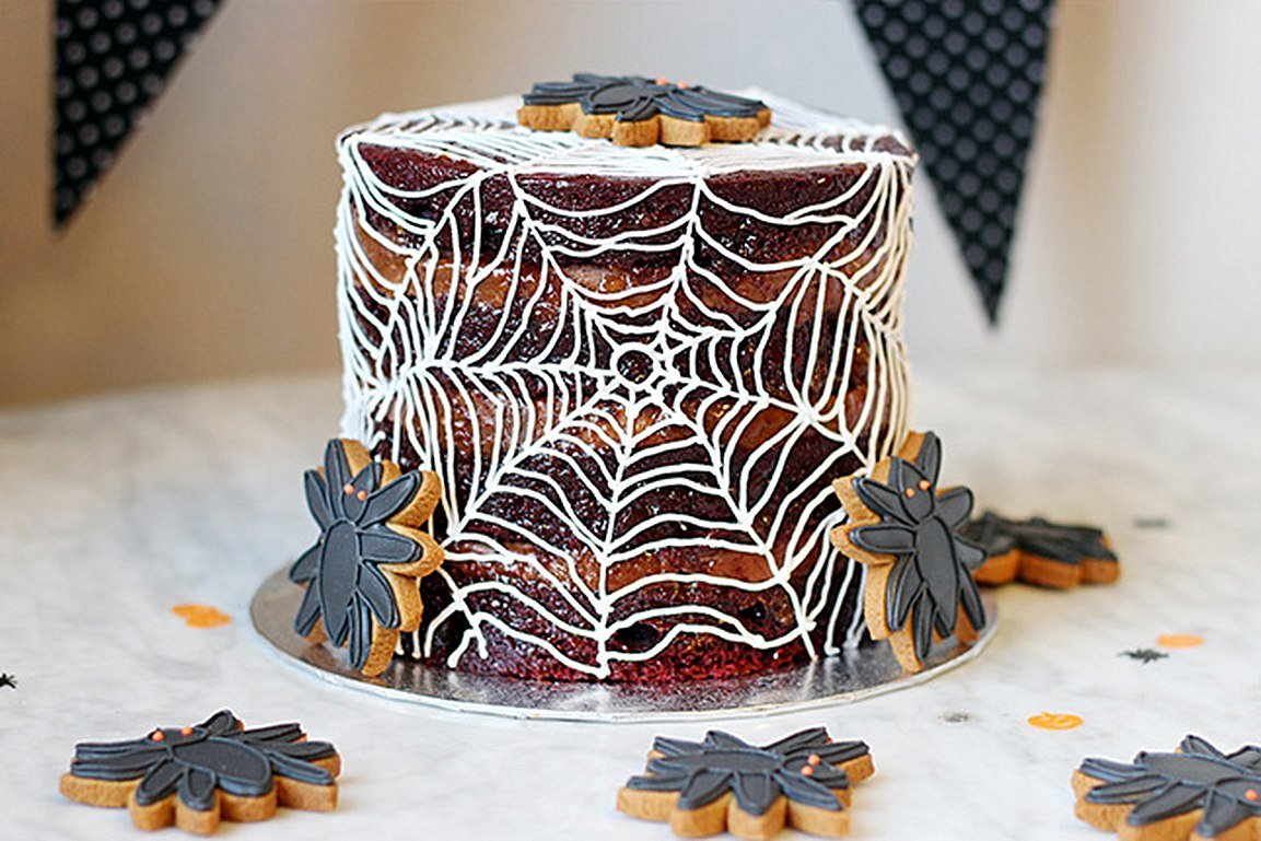 Halloween red velvet cake with spider web icing and black spider biscuits, perfect for Biscuiteers' spooky season treats.