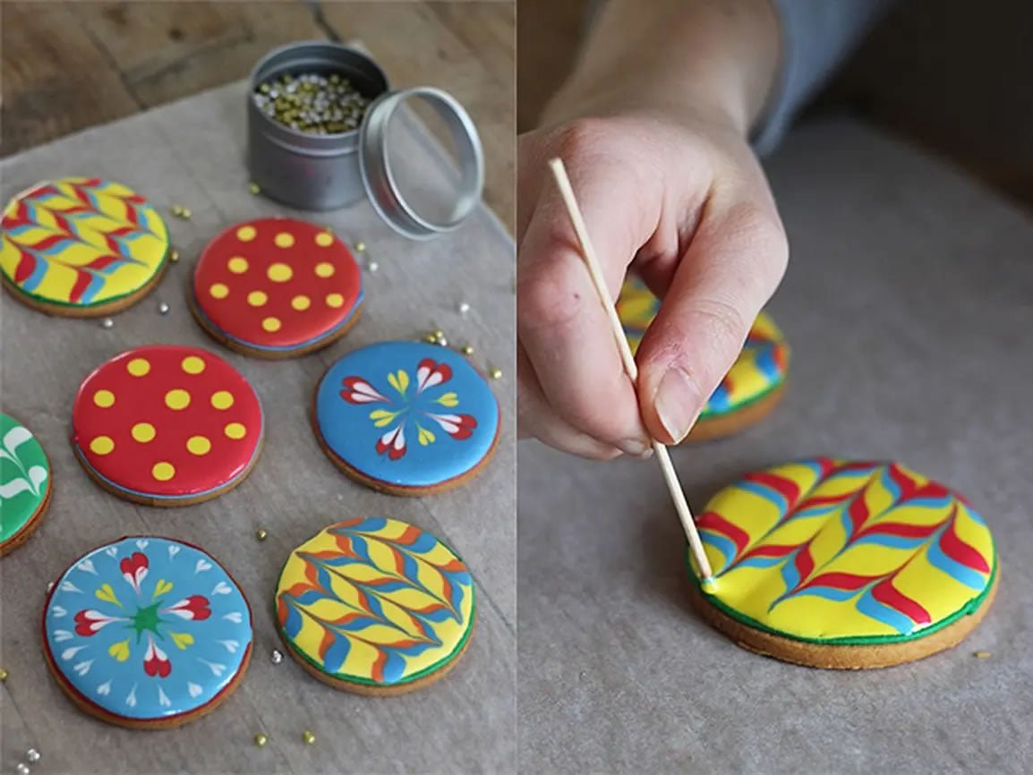 Flood icing techniques on biscuits with dots, zig-zag, and feathering for personalized gifts by Biscuiteers.