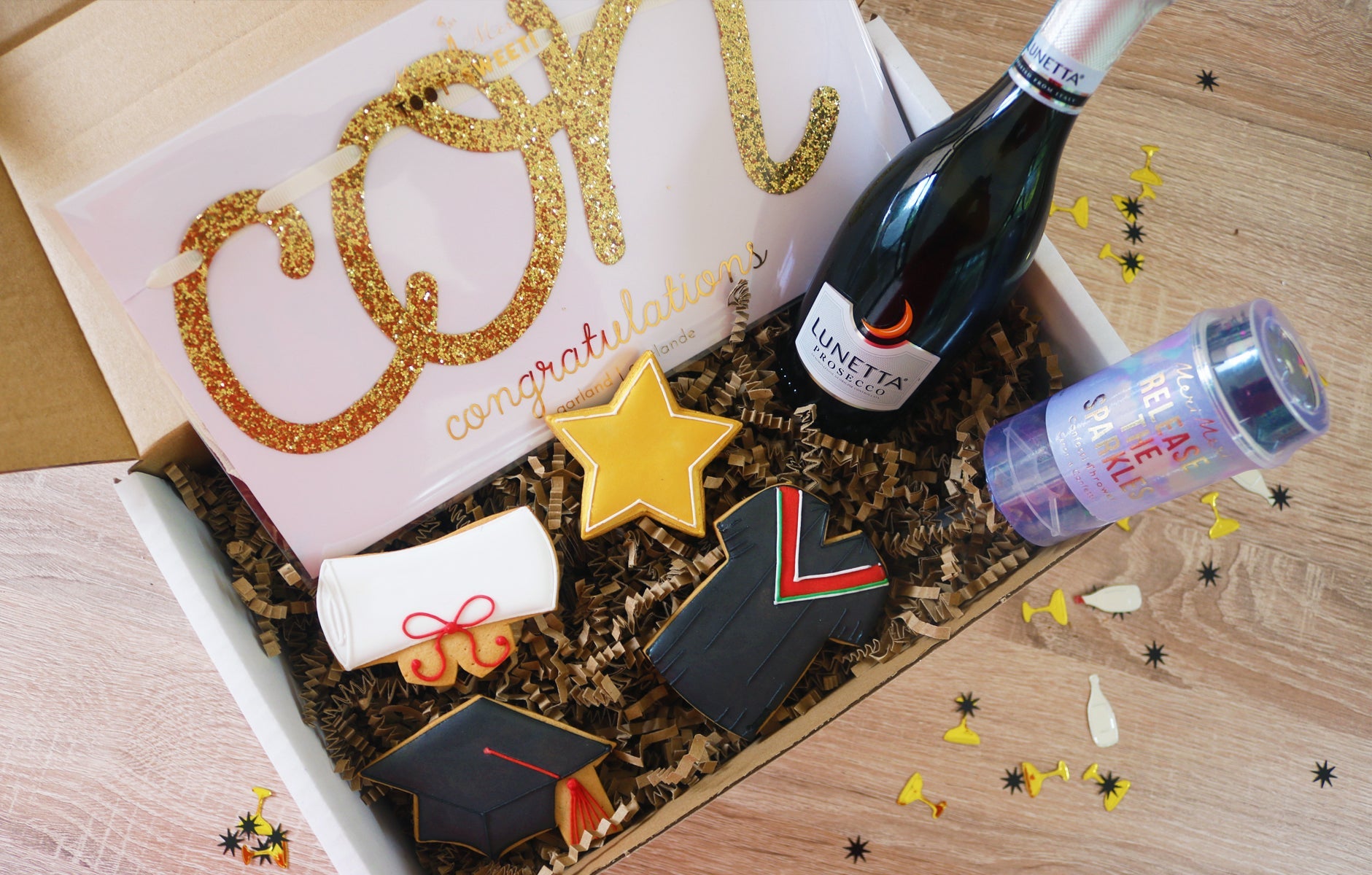 Graduation celebration box with biscuits, prosecco, and banner by Biscuiteers for personalized gifting during pandemic.