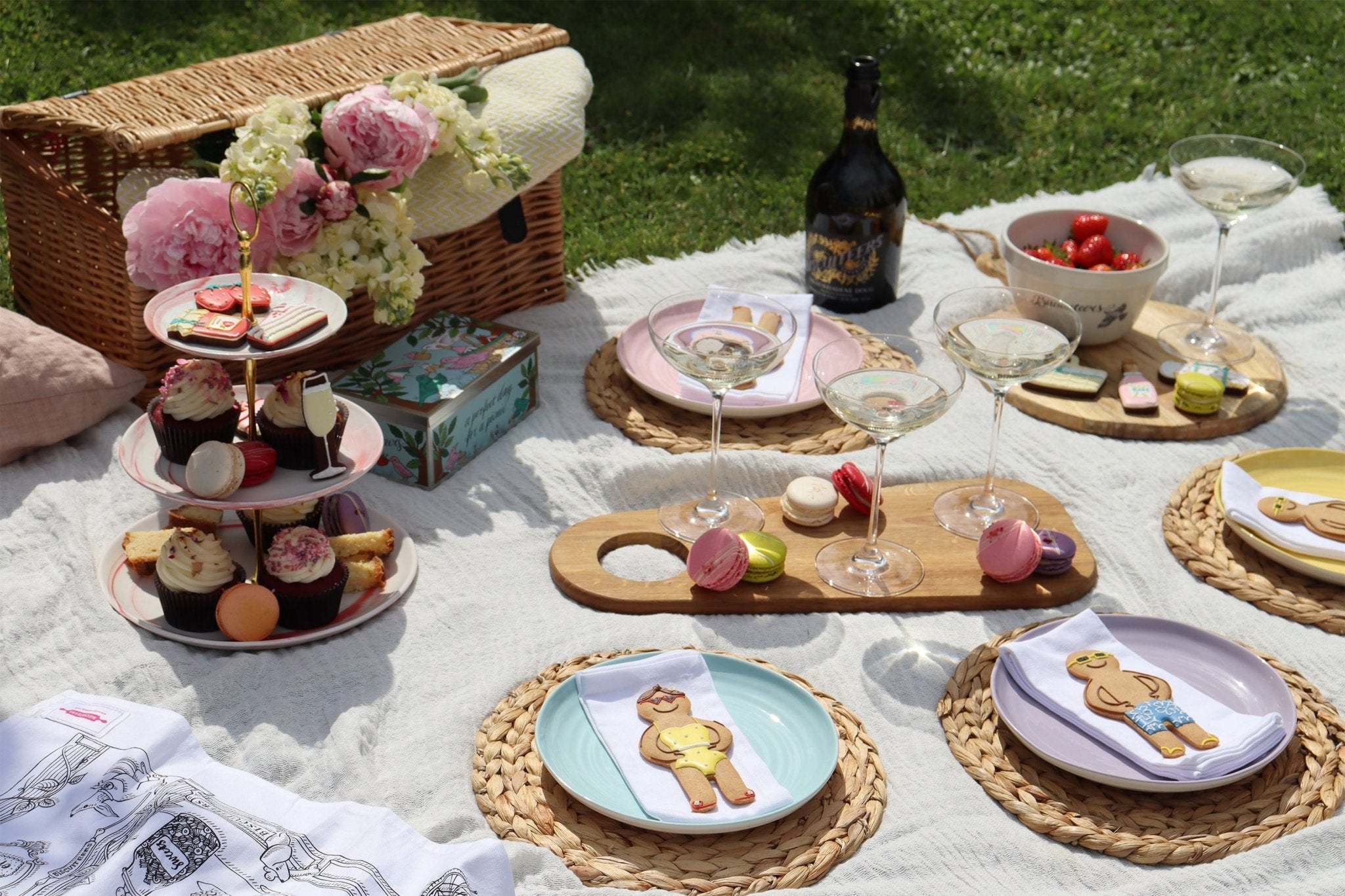 Biscuiteers summer picnic essentials: wicker hamper, personalized biscuits, and treats for a perfect sunny day gathering.