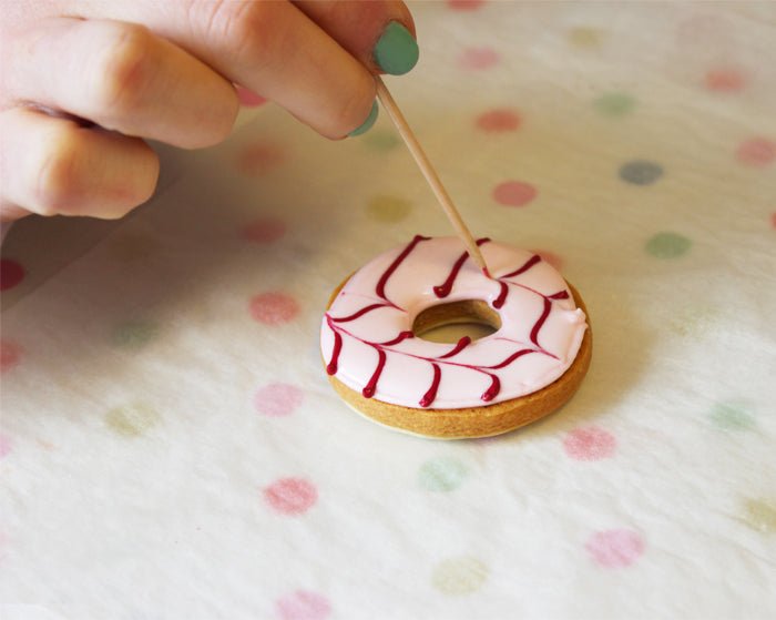 Colorful iced party ring biscuits with feathered icing technique, perfect for special occasions and personalized gifts by Biscuiteers.