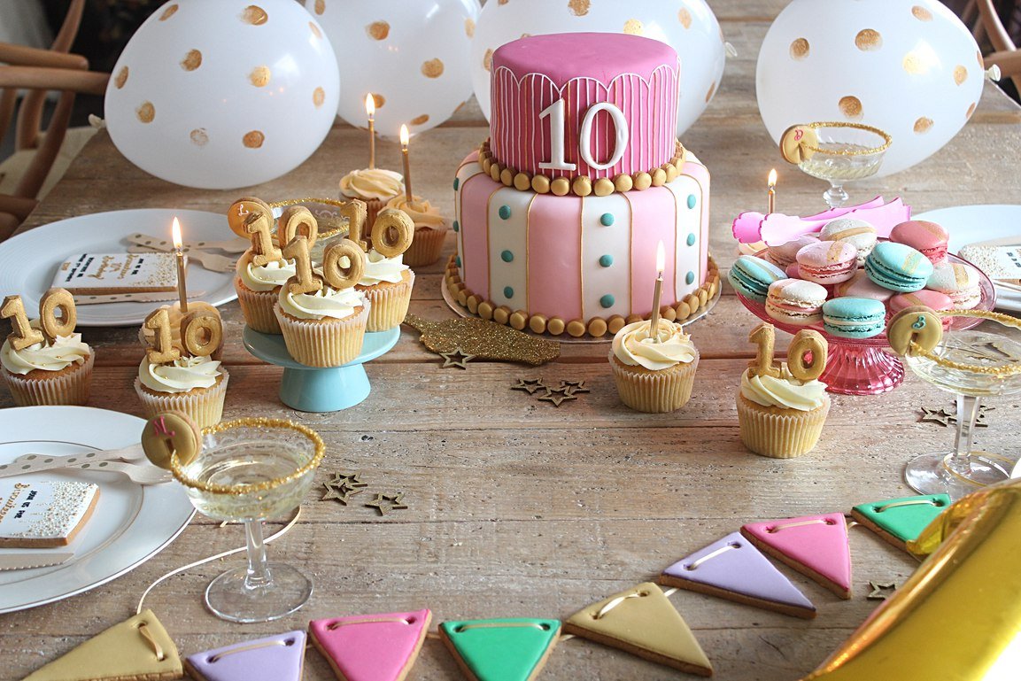 Biscuiteers 10th birthday party setup with tiered cake, gold spot balloons, and personalized biscuit invites for celebrations.
