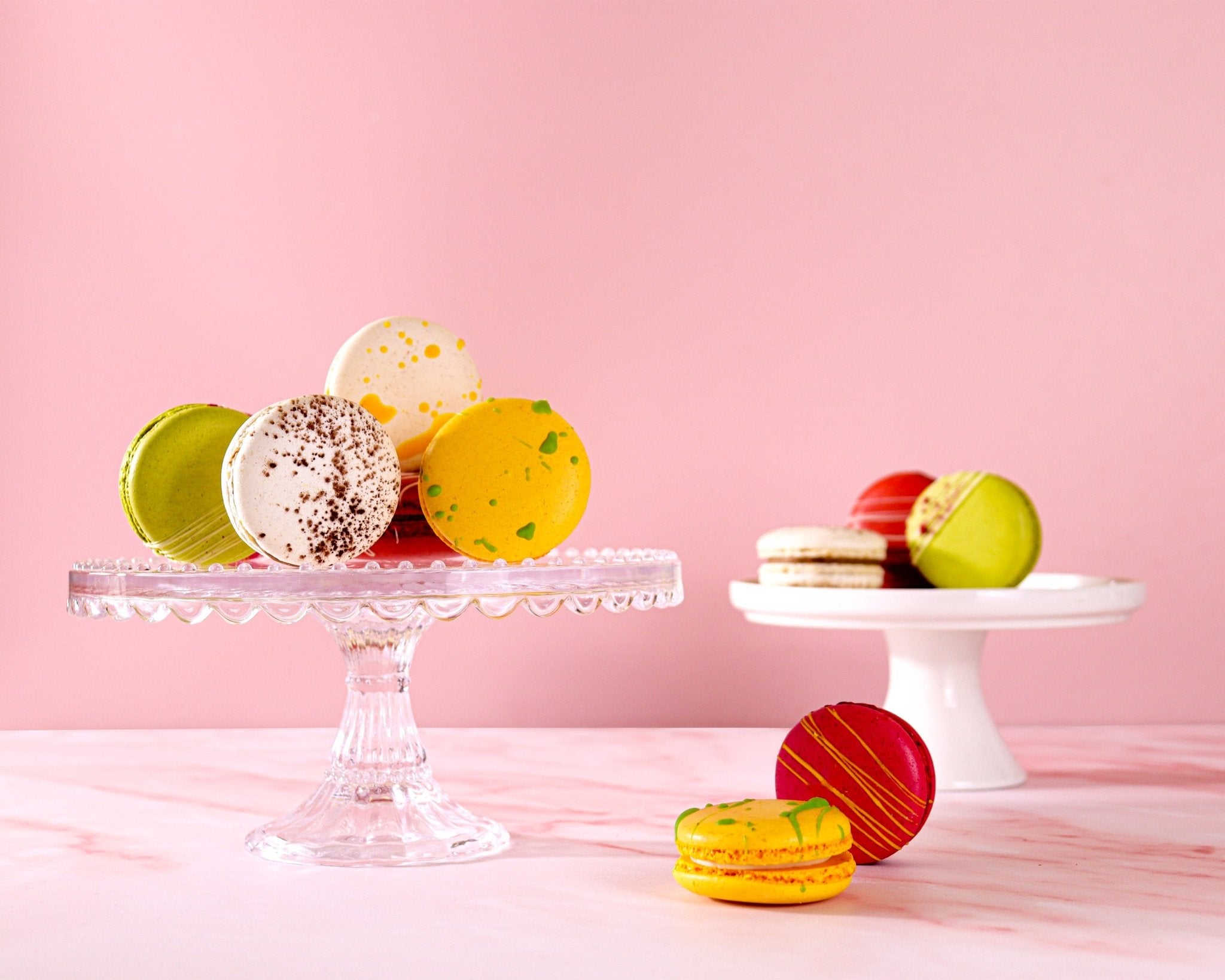 Spring macarons by Biscuiteers: yellow, green, and white designs on a glass plate, perfect for personalized gifts.