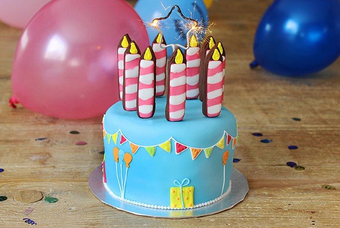 Hand-iced biscuit pops shaped like birthday candles, perfect for celebrations, from Biscuiteers' bestselling collection.