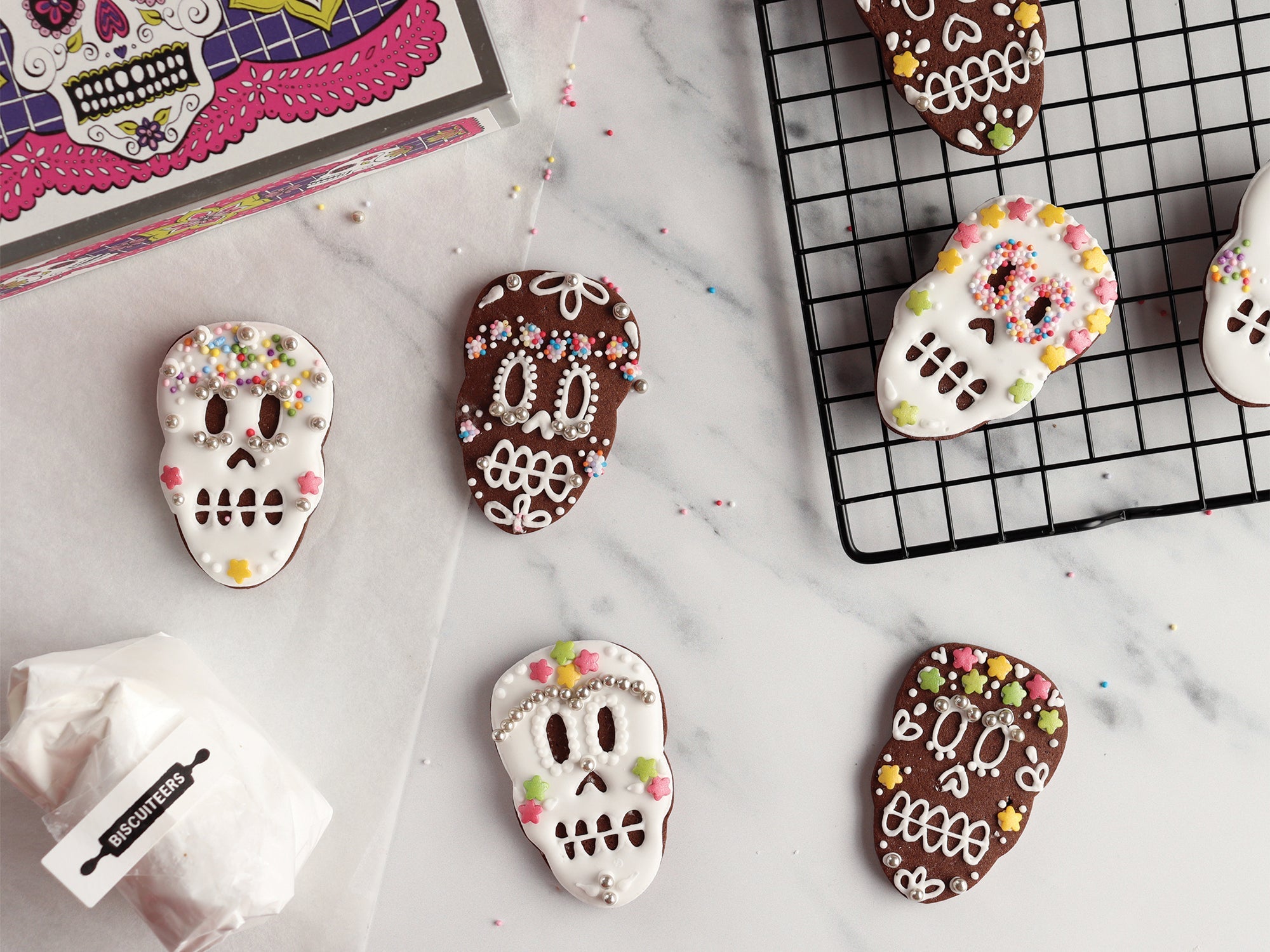 Halloween-themed Biscuiteers DIY Skulls Biscuit Tin with decorated sugar skulls, perfect for spooky parties and personalized gifts.