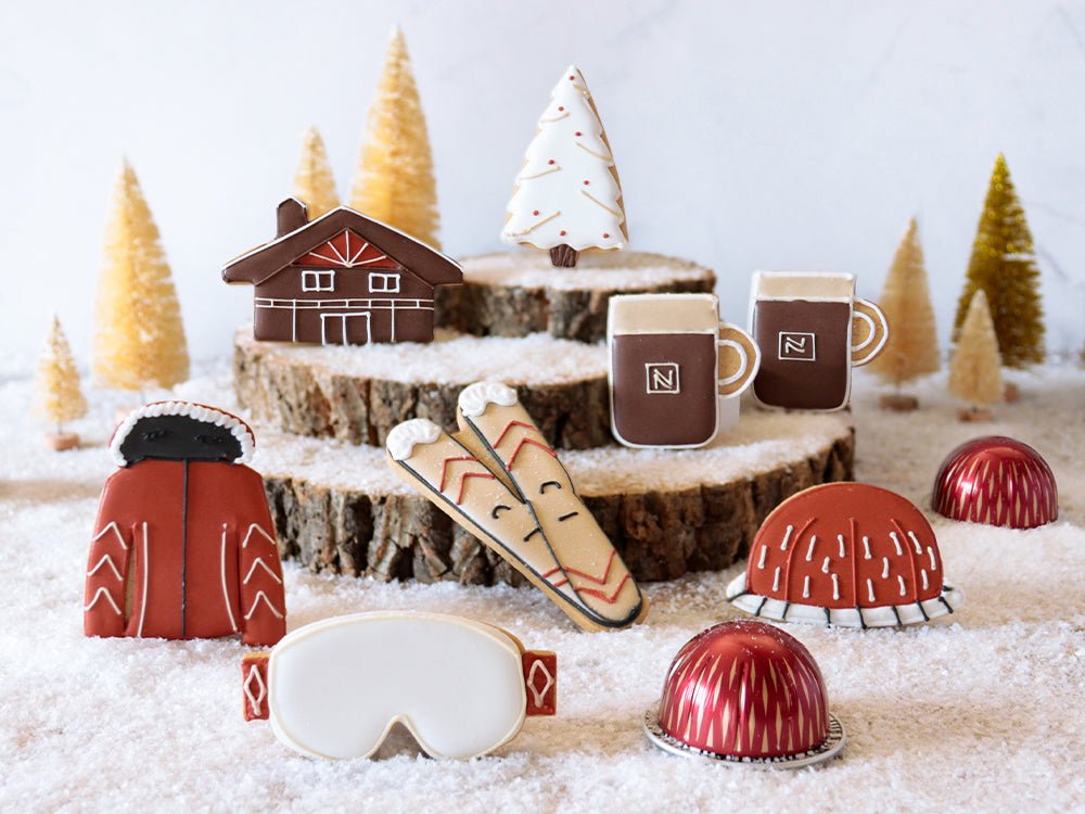 Festive Biscuiteers and Nespresso Après Ski biscuits with red, cream, brown, and gold icing, perfect for holiday gifts.