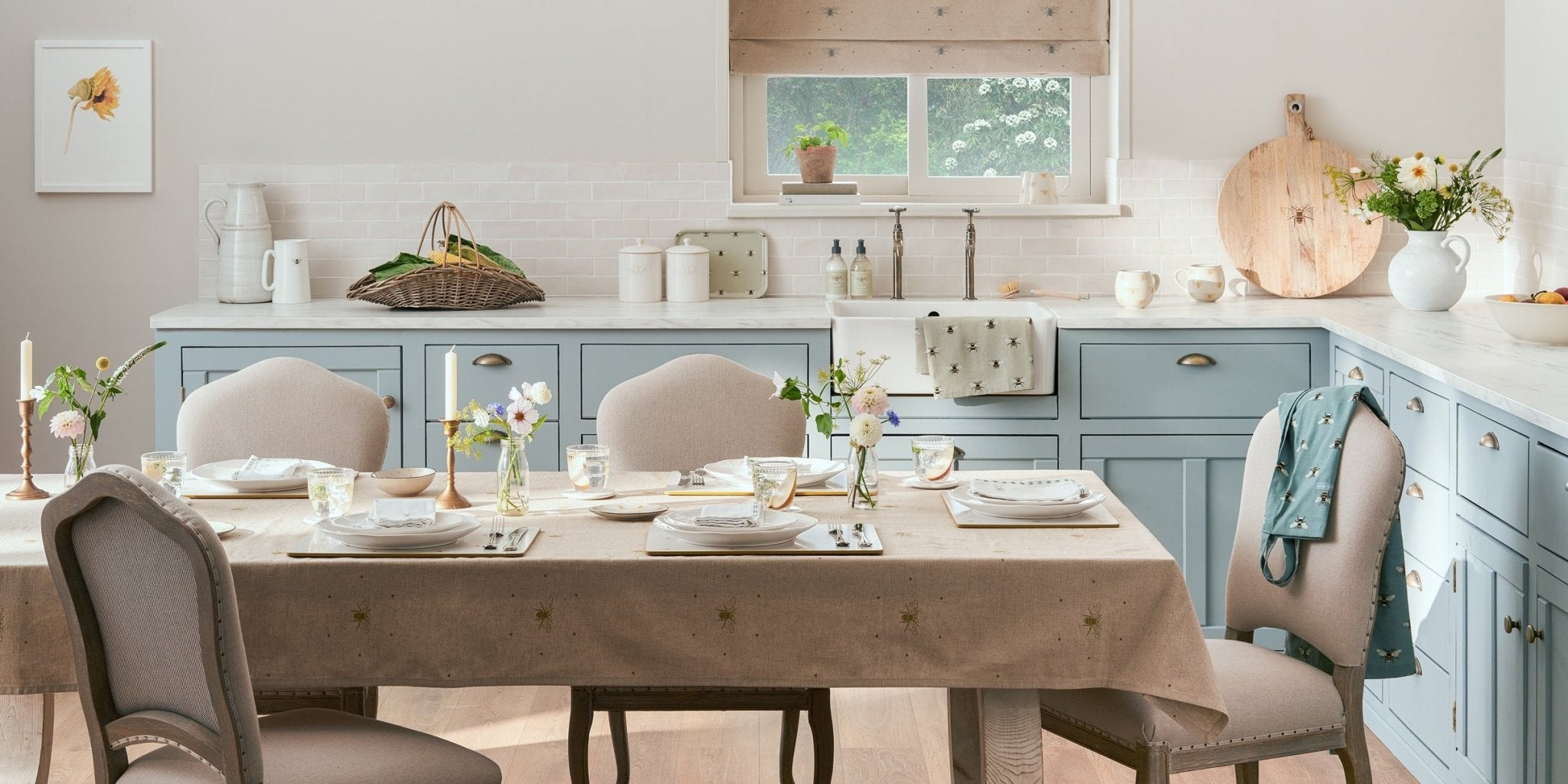 Spring tablescape with Biscuiteers' bee-themed crockery, vibrant flowers, and Sophie Allport linens for personalized dining.