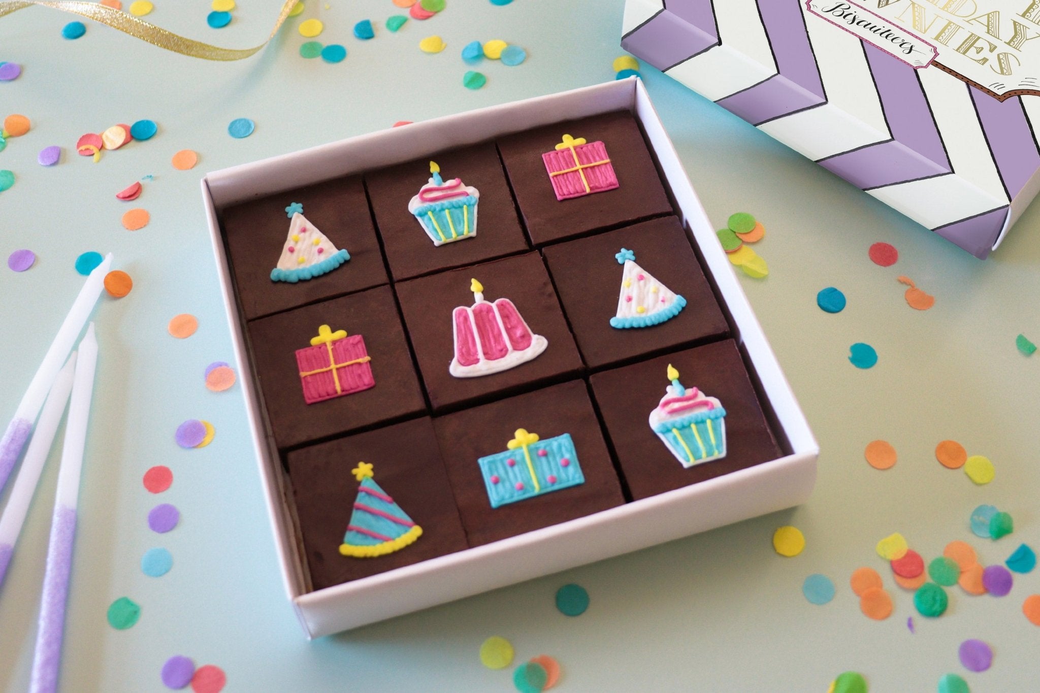 Hand-iced birthday brownies with glossy ganache, perfect for Biscuiteers' 16th celebration and personalized gift giving.