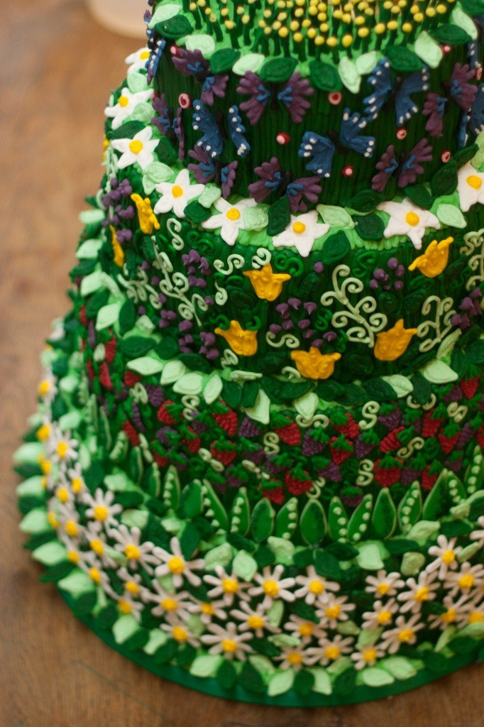 Four-tiered wedding cake with hand-iced daisies, tulips, and butterflies by Biscuiteers for a summer floral-themed wedding.